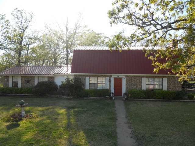 Shows a full picture of the entire house from the front with the red metal reroof